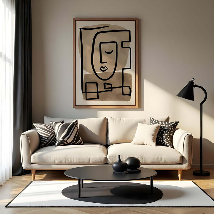 Picasso Face in Silence framed above a neutral beige sofa with monochrome cushions in a warm modern interior.